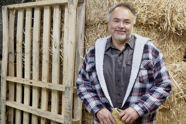 Portrait of happy mature male standing in front of hay stack — Stock Photo, Image