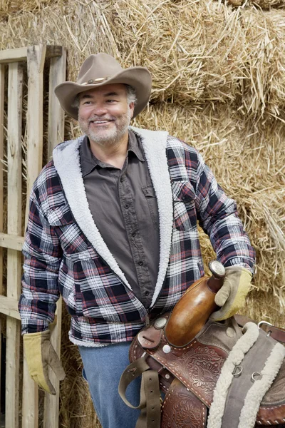 Felice maturo cowboy holding sella — Foto Stock