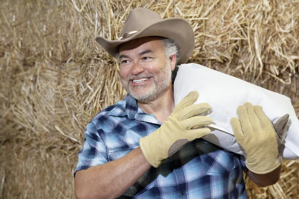 Felice maturo cowboy portando sacco sulla spalla, mentre guardando lontano — Foto Stock