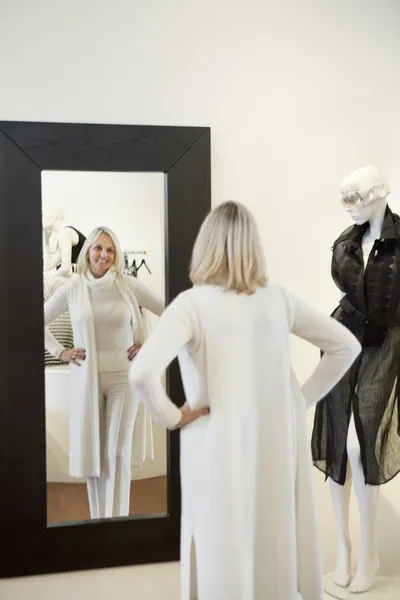 Vue arrière d'une femme âgée debout avec les mains sur les hanches en face du miroir se regardant — Photo