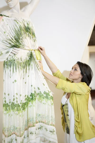 Beautiful mid adult woman adjusting dress on mannequin in clothing store — Stock Photo, Image