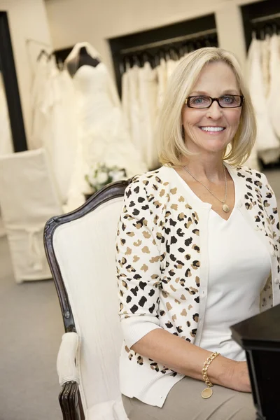 Porträtt av en glad äldre kvinna som bär glasögon som sitter i bröllopsbutiker boutique — Stockfoto