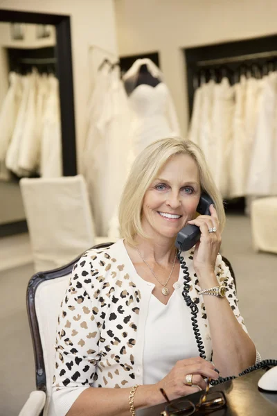 Portrait d'une femme heureuse écoutant un récepteur téléphonique en magasin nuptial — Photo