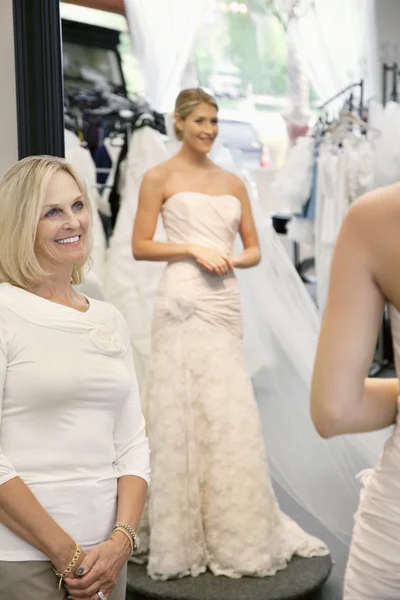 Mère heureuse admirant fille vêtue d'une robe de mariée — Photo