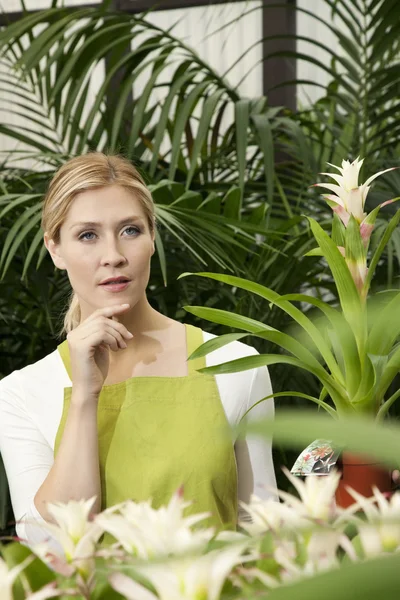 Thoughtful young woman in greenhouse — Stock Photo, Image