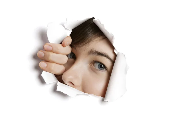 Portrait of a young Middle eastern woman peeking from ripped white paper hole — Stock Photo, Image