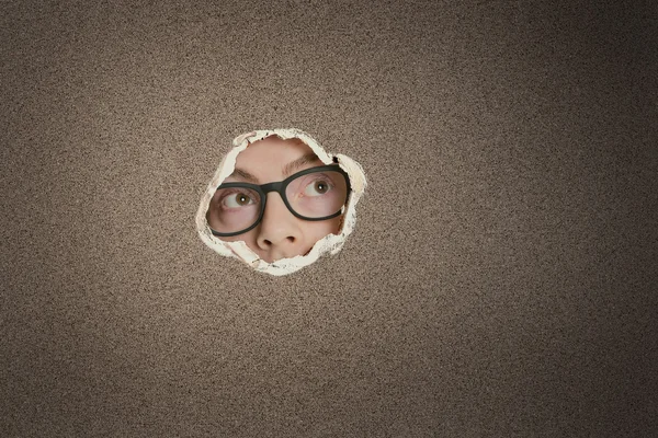 Mid adult Caucasian man looking away from ripped paper hole — Stock Photo, Image