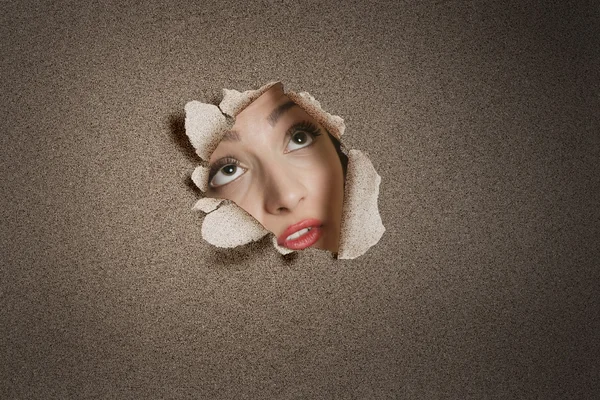 Young Middle eastern woman looking up from ripped paper hole — Stock Photo, Image