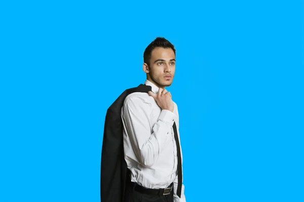 Уверенный молодой бизнесмен в костюме за плечом на цветном фоне — стоковое фото