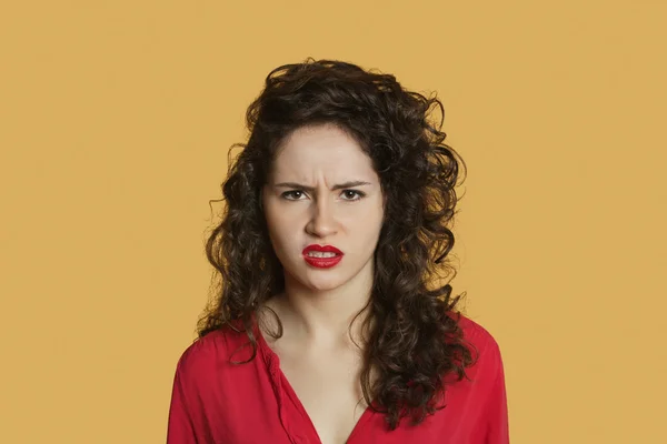 Portrait de jeune femme en colère fronçant les sourcils sur fond coloré — Photo