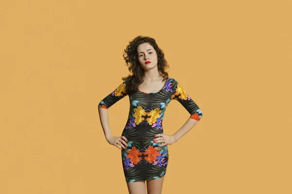 Porträt einer selbstbewussten jungen Frau, die mit Händen auf Hüften vor farbigem Hintergrund posiert — Stockfoto