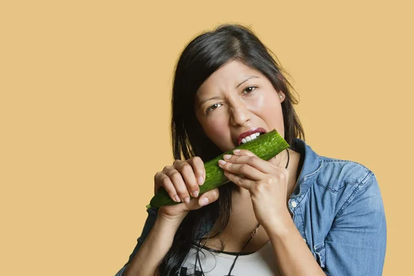 Renkli arka plan üzerinde salatalık yemeyi bir genç kadının portresi — Stok fotoğraf