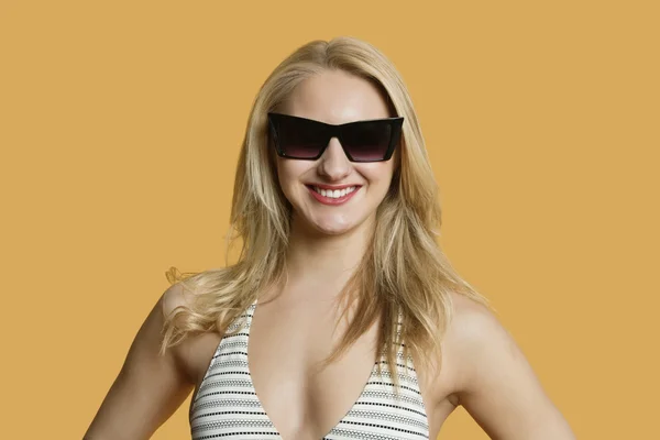Retrato de una hermosa joven en bikini con gafas de sol sobre fondo de color — Foto de Stock