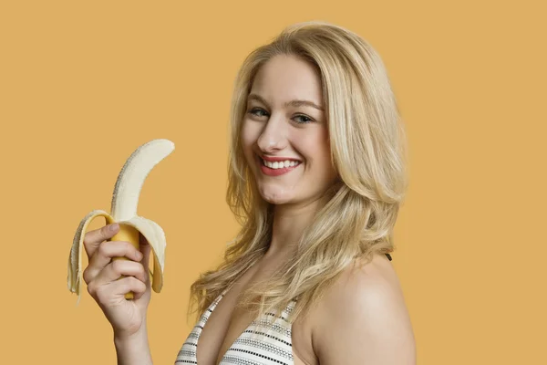 在彩色背景吃香蕉年轻女子肖像 — 图库照片