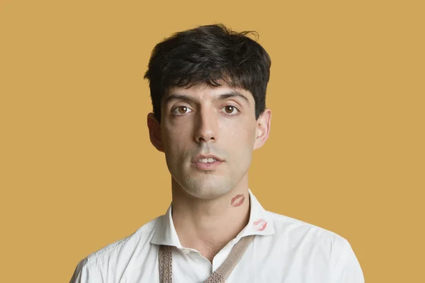 Portrait of a young man with lip print on neck and shirt over colored background — Stock Photo, Image