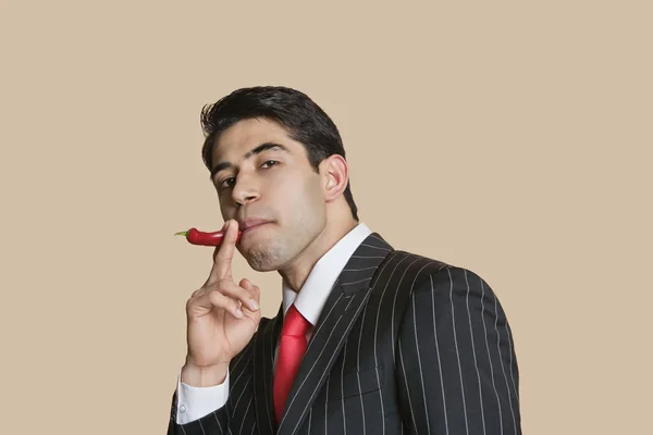 Portrait of a young businessman with red chili pepper imitating as smoking cigarette — Stock Photo, Image