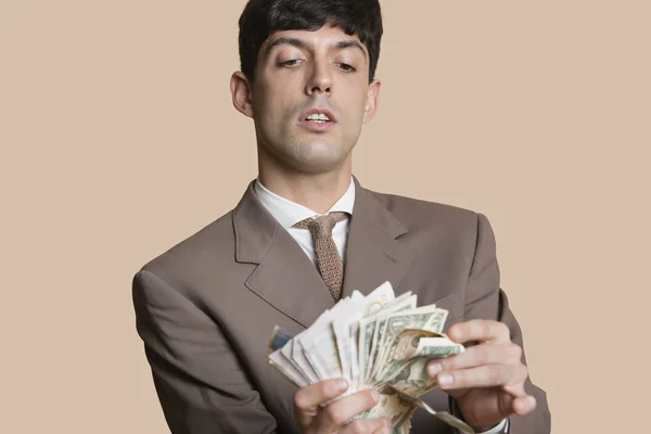 Young businessman counting money over colored background — Stock Photo, Image