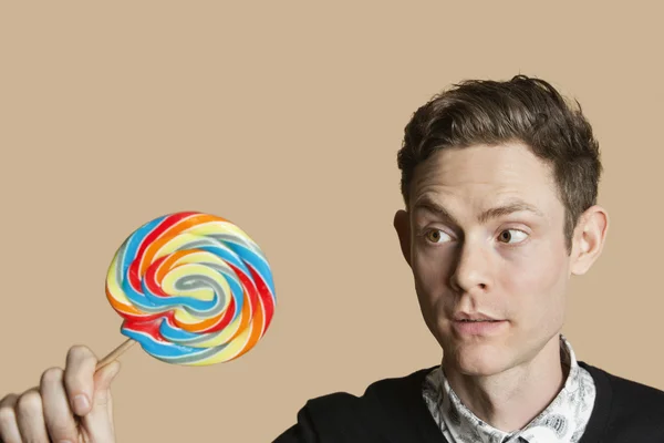 Mitten av vuxen man tittar på lollipop över färgad bakgrund — Stockfoto