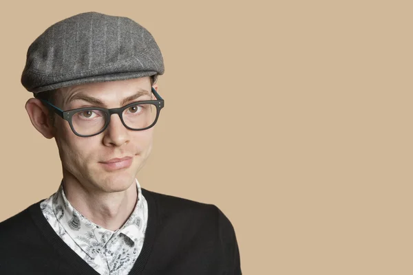 Portrait of a mid adult man wearing retro glasses and cap over colored background — Stock Photo, Image