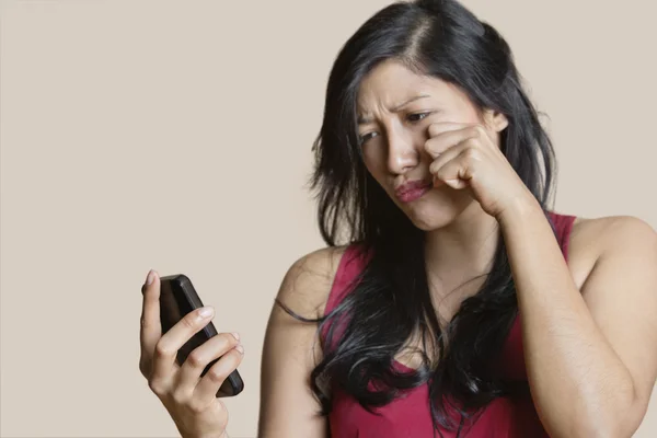 Triste jovem olhando para o telefone celular sobre fundo colorido — Fotografia de Stock