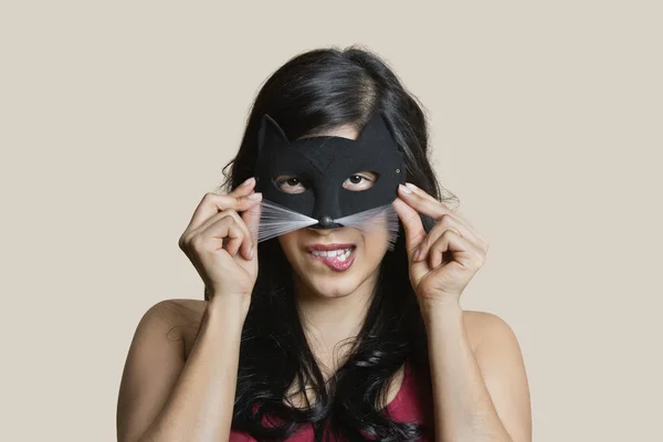 Porträtt av en ung kvinna som bär eye mask medan bita läpp över färgad bakgrund — Stockfoto