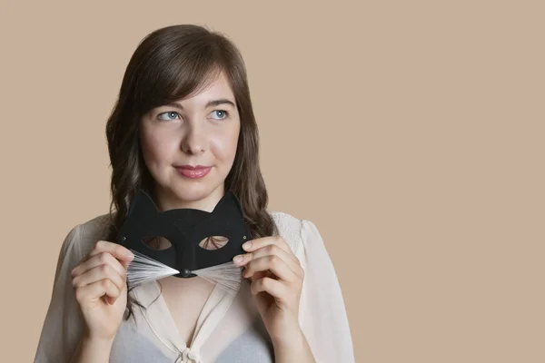 Jonge vrouw met oog masker terwijl kijken weg over gekleurde achtergrond — Stockfoto
