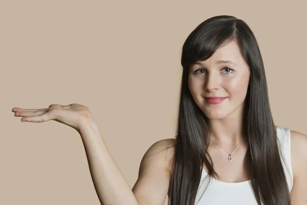 Portret van een mooie jonge vrouw met lege hand over gekleurde achtergrond — Stockfoto