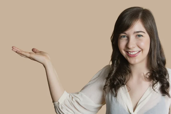 Portrait of a happy young woman with empty hand over colored background — Stock Photo, Image