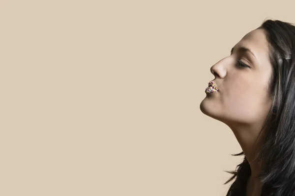 Side view of young woman with sprinkled lips while looking away over colored background — Stock Photo, Image