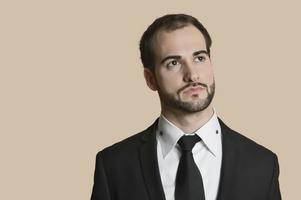 Junger Geschäftsmann blickt über farbigen Hintergrund hinweg — Stockfoto