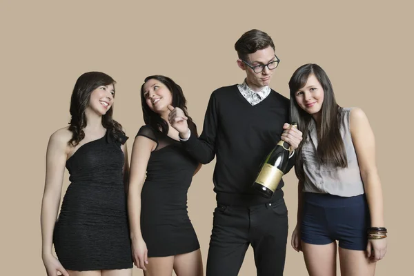 Retrato de homem adulto médio e mulheres jovens segurando garrafa de champanhe sobre fundo colorido — Fotografia de Stock