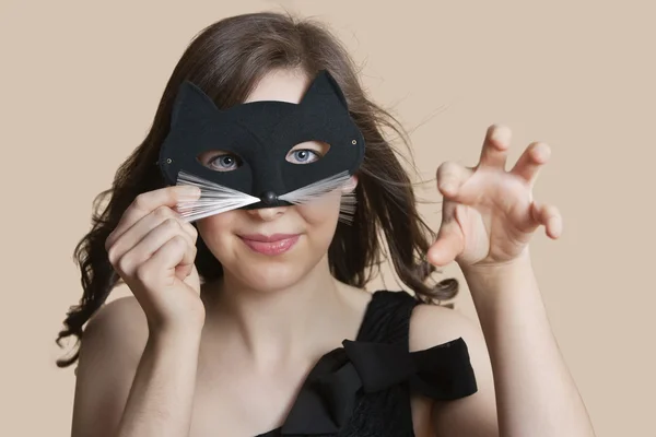 Göz maskesi kedi kadar renkli arka plan üzerinde taklit yoluyla arayan genç bir kadın portresi — Stok fotoğraf