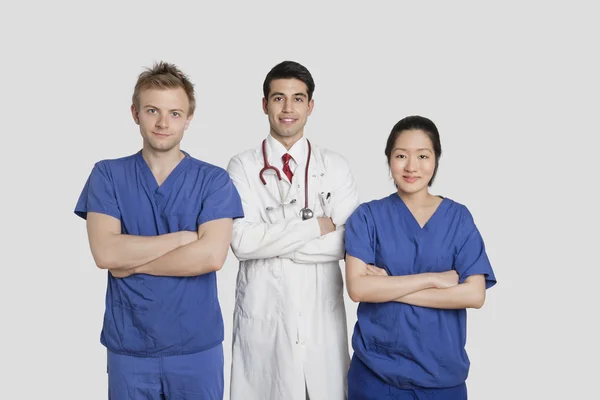 Portrait of diverse healthcare workers standing with hands folded over gray background — Stock Photo, Image