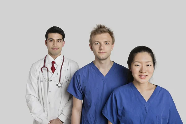 Retrato de equipe médica multi étnica confiante em pé sobre fundo cinza — Fotografia de Stock