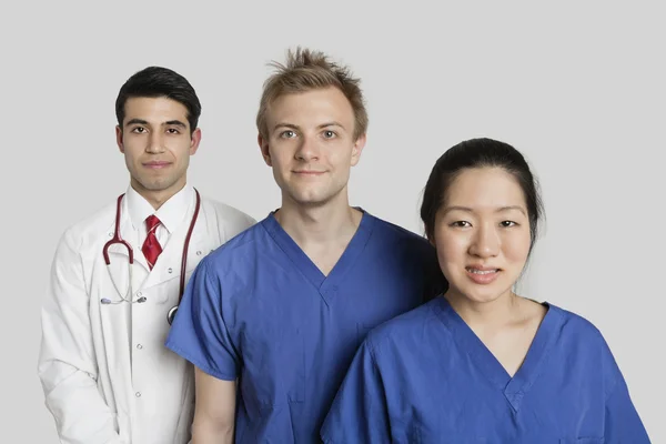 Retrato de equipe médica diversificada em pé sobre fundo cinza — Fotografia de Stock