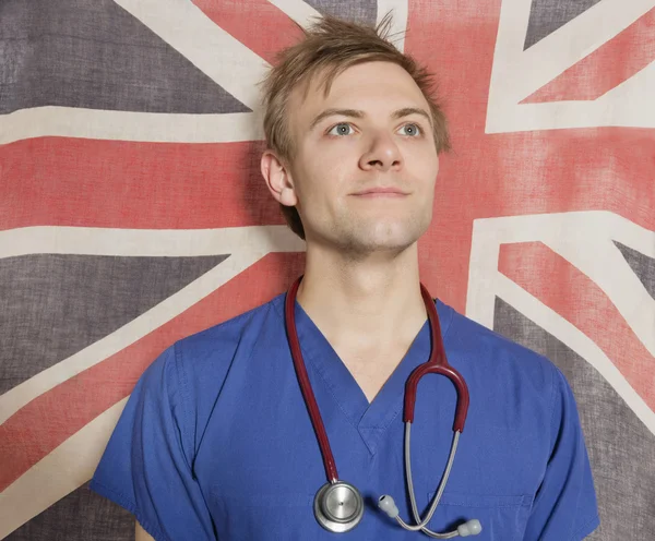 Cirurgião masculino confiante olhando para cima com bandeira britânica no fundo — Fotografia de Stock