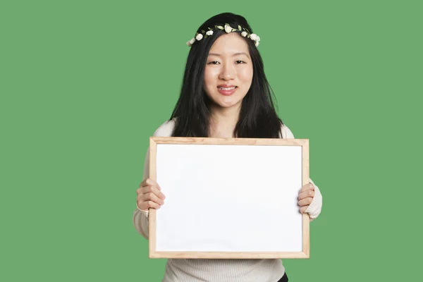 Retrato de uma jovem segurando um quadro branco sobre fundo verde — Fotografia de Stock