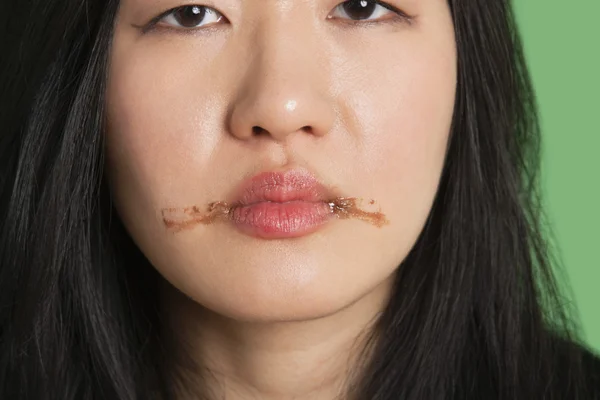 Portret van een jonge vrouw met chocolade vlekken rond haar lippen — Stockfoto