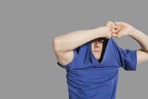 Young man removing t-shirt over colored background — Stock Photo, Image