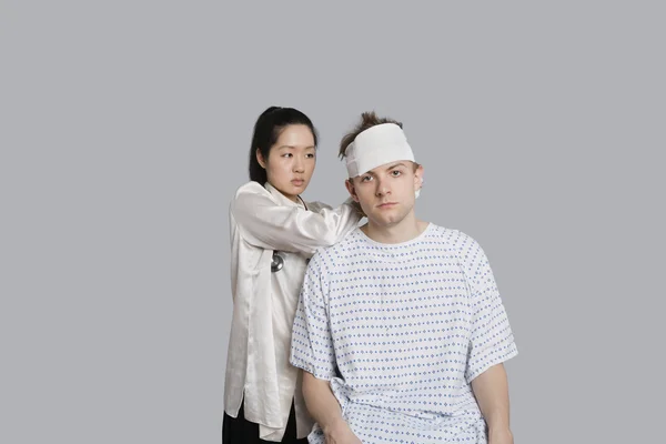 Женщина-врач одевает голову пациента бинтом — стоковое фото