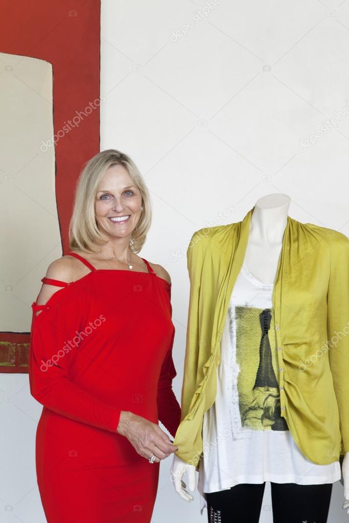Portrait of a beautiful young woman standing by mannequin in fashion store