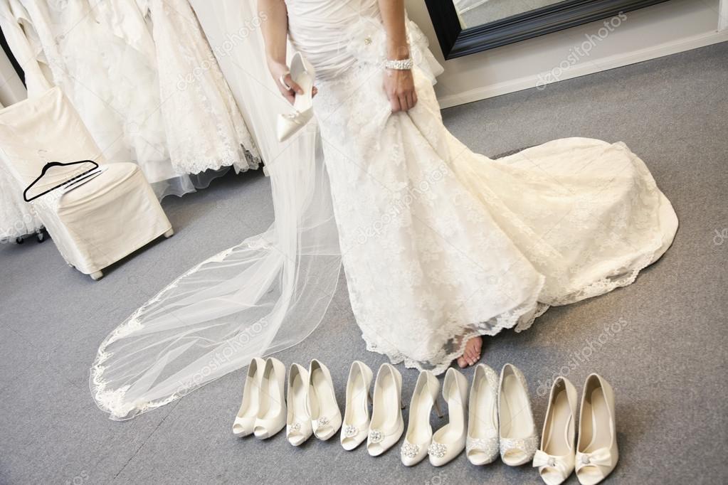 Low section of young woman standing with variety of footwear in bridal boutique