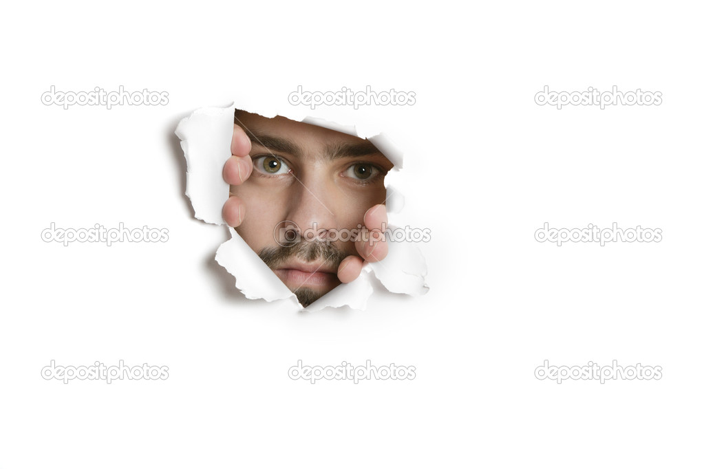 Portrait of a mid adult Caucasian man peeking from ripped paper hole