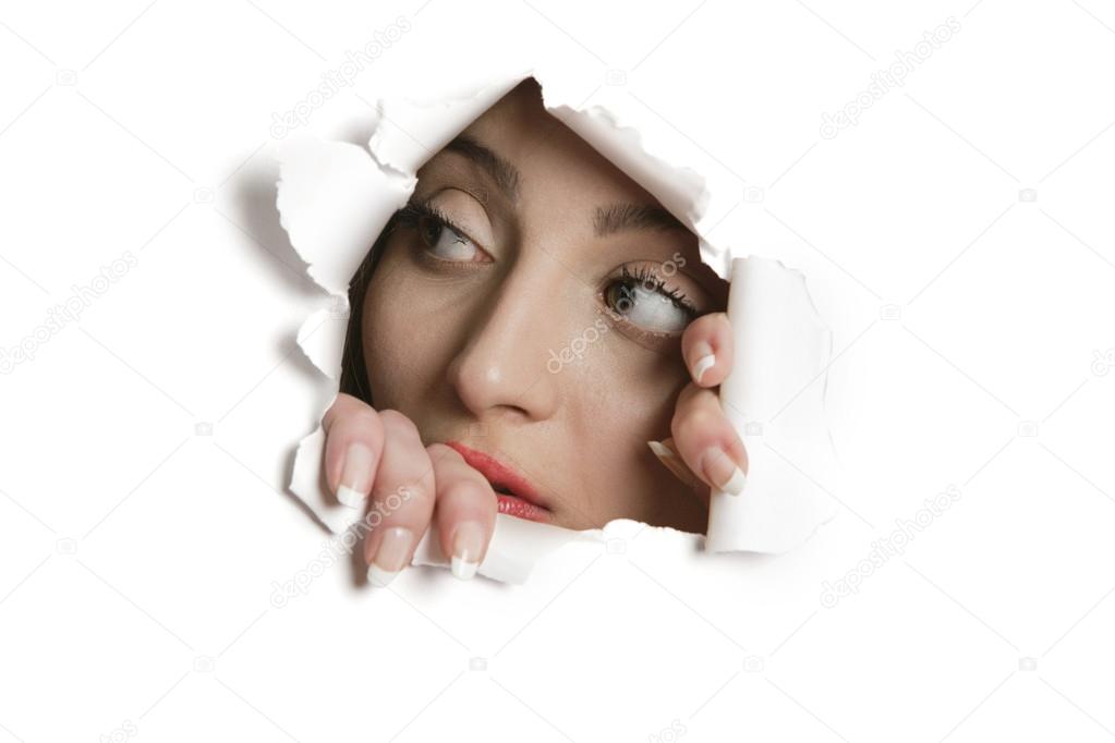 Young Middle eastern woman looking away from ripped paper hole