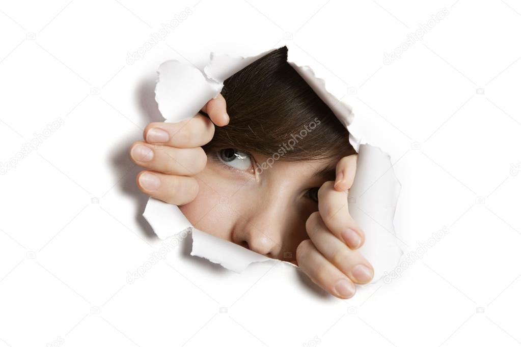 Young Middle eastern woman peeking from ripped white paper hole