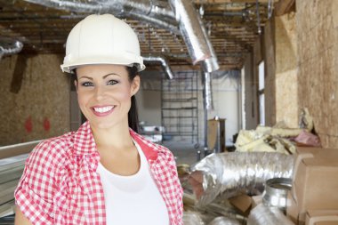 Close-up portrait of smiling young woman contractor at construction site
