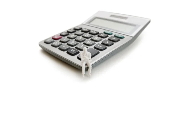 Figura manekin małych siedzi na kalkulatorze na białym tle — Zdjęcie stockowe