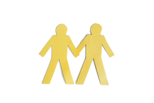 Two yellow paper cut out figures holding hands over white background — Stock Photo, Image
