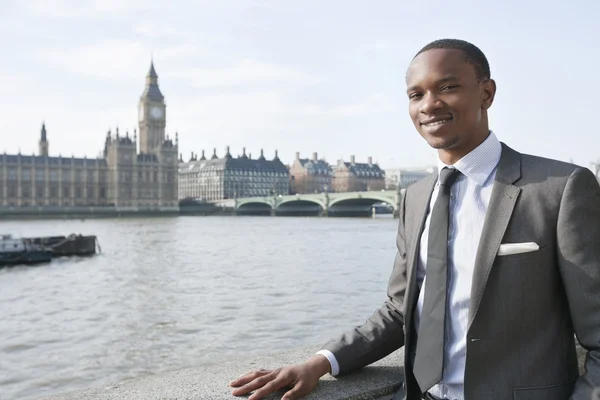 Portret van een glimlachende Afro-Amerikaanse zakenman met gebouwen in de achtergrond — Stockfoto