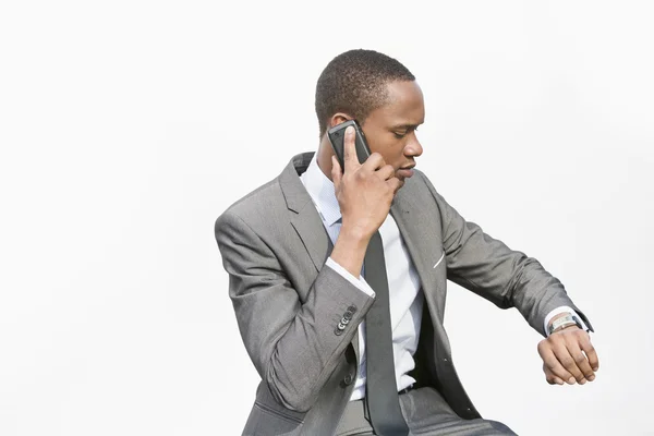 Афроамериканский бизнесмен проверяет время во время звонка — стоковое фото